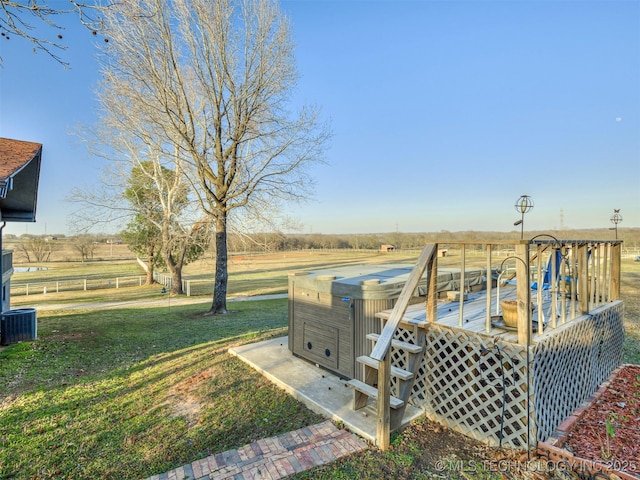 view of yard with a rural view, a deck, and a hot tub