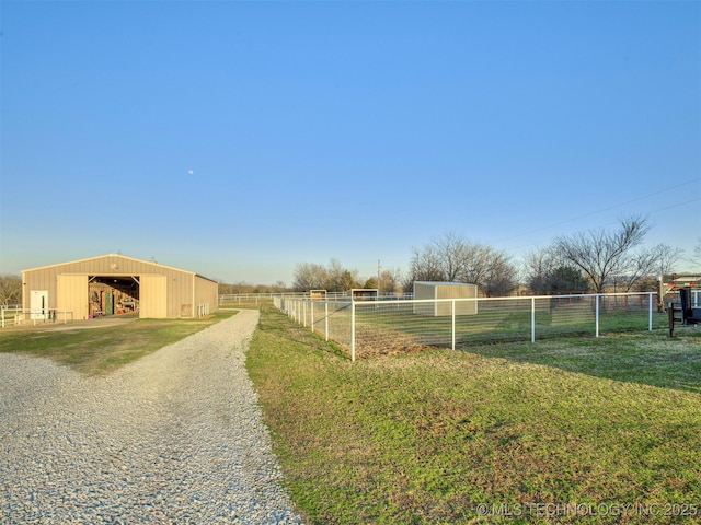 view of yard featuring an outbuilding, a detached garage, fence, a rural view, and a pole building