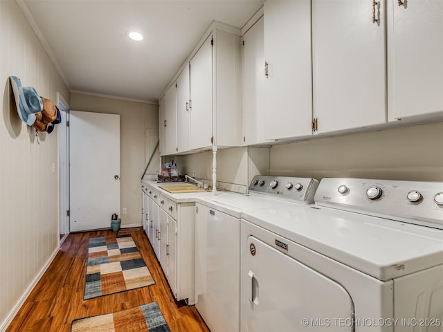 laundry area featuring washer and clothes dryer, a sink, wood finished floors, cabinet space, and crown molding