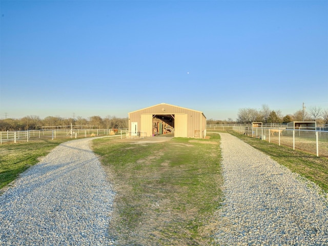 view of pole building featuring a rural view, fence, and driveway