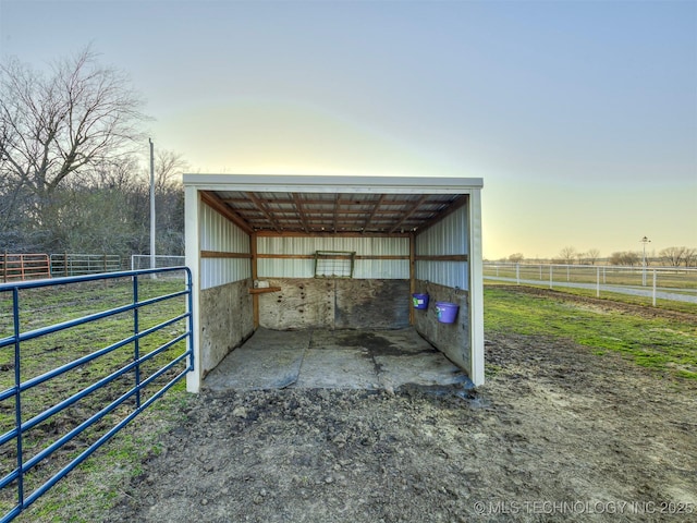 outdoor structure at dusk featuring an outbuilding, a rural view, an exterior structure, and a carport