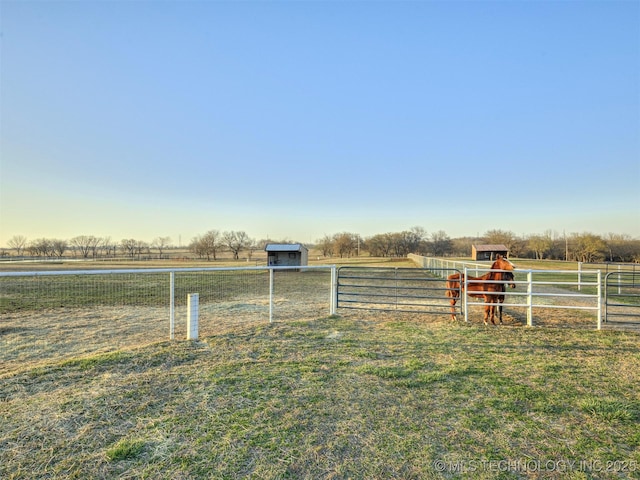 view of yard featuring an outbuilding, a rural view, and fence