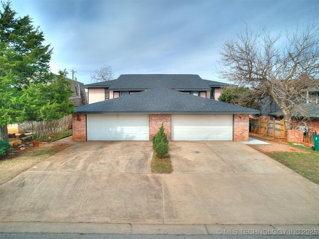 view of front facade featuring a detached garage, brick siding, roof with shingles, and fence