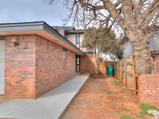 view of side of property featuring brick siding and fence
