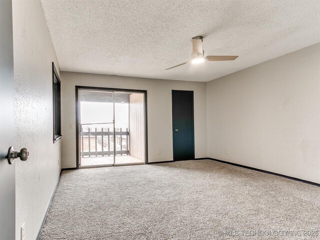 carpeted spare room with a ceiling fan, baseboards, a textured wall, and a textured ceiling
