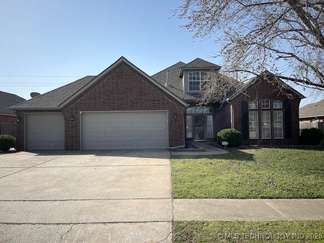 traditional-style house with a front lawn, an attached garage, brick siding, and driveway