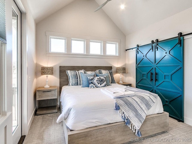 bedroom featuring a barn door, multiple windows, carpet, and vaulted ceiling