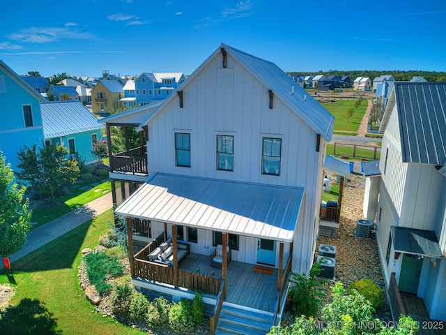 rear view of house with covered porch, board and batten siding, metal roof, and a balcony