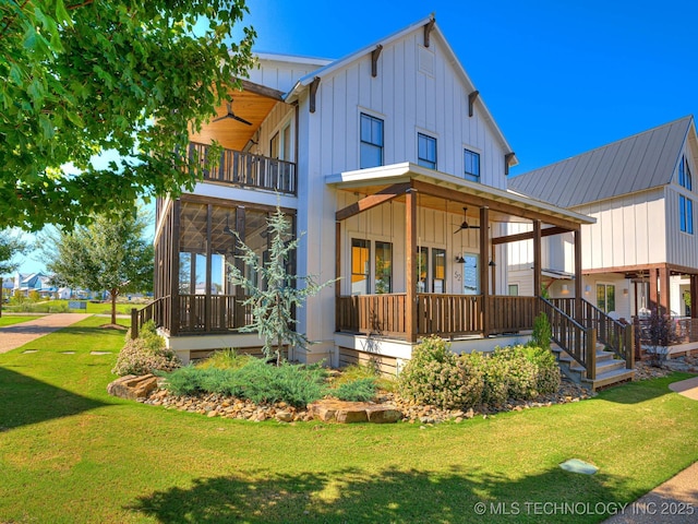 view of front facade with a front yard, a balcony, covered porch, ceiling fan, and board and batten siding