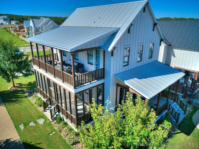 back of property featuring a lawn, board and batten siding, and metal roof