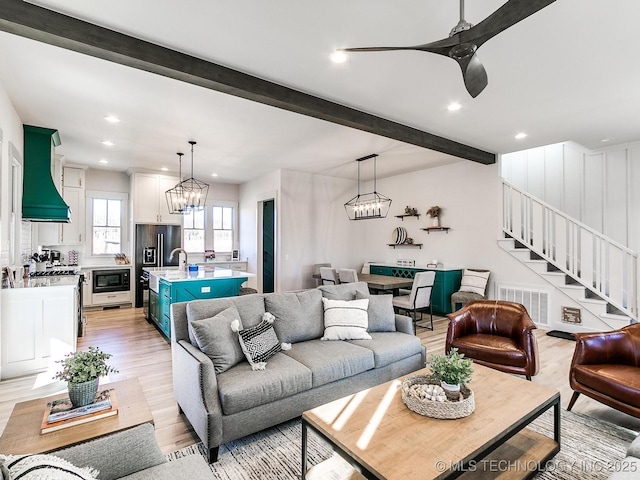 living area featuring stairway, beamed ceiling, recessed lighting, and light wood-style floors