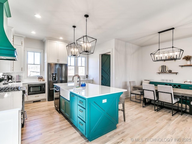 kitchen featuring light countertops, light wood-style floors, a notable chandelier, white cabinetry, and a sink