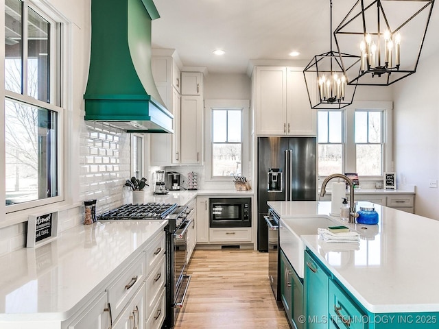 kitchen with backsplash, black microwave, a chandelier, stainless steel gas range, and wall chimney exhaust hood