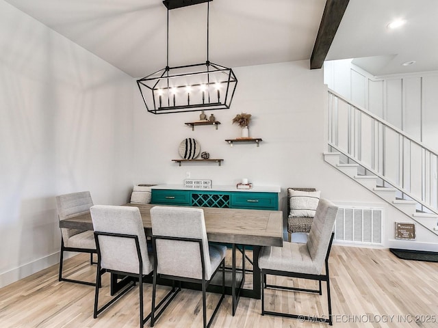 dining space with beamed ceiling, light wood-style flooring, stairs, and baseboards