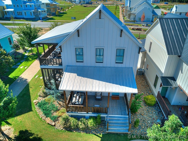 rear view of property featuring central air condition unit, a residential view, board and batten siding, covered porch, and a balcony