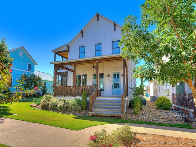 view of front of property with a ceiling fan, a porch, cooling unit, board and batten siding, and a front yard