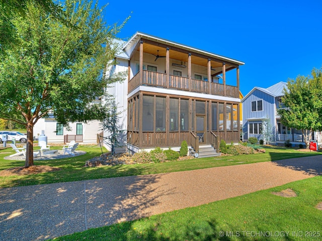 view of front facade featuring a balcony, a front yard, and a sunroom