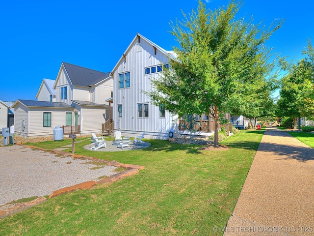 view of front of house featuring gravel driveway, a front yard, board and batten siding, and metal roof