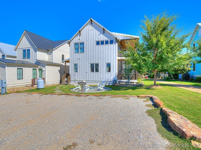 view of front of home with entry steps, a front yard, a balcony, and board and batten siding