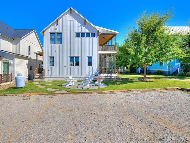 rear view of property featuring a balcony, a lawn, board and batten siding, and central AC