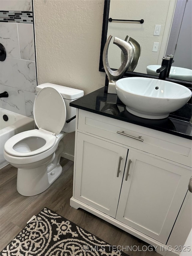 full bathroom with vanity, wood finished floors, shower / bath combination, toilet, and a textured wall