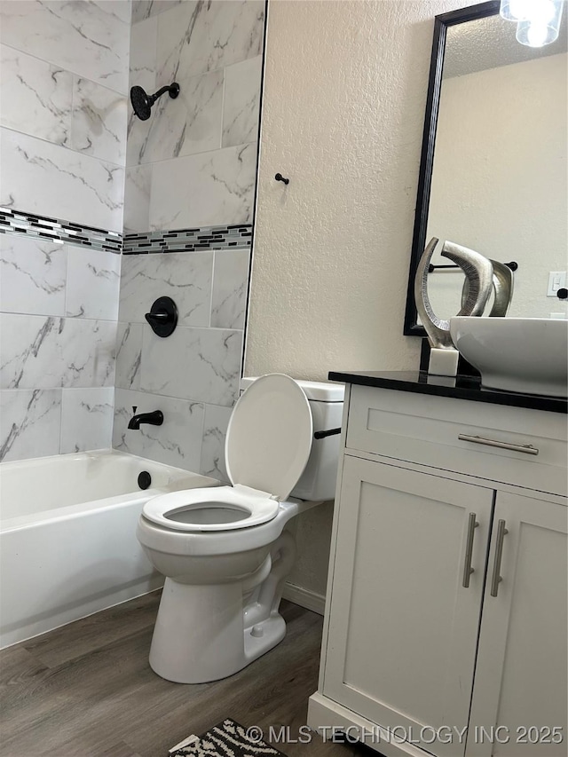 bathroom featuring wood finished floors, vanity, shower / bathing tub combination, and a textured wall