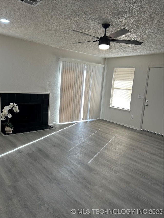 unfurnished living room featuring wood finished floors, a ceiling fan, and a textured ceiling