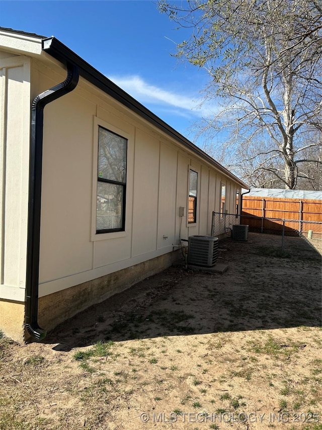 view of home's exterior featuring central air condition unit, board and batten siding, and fence