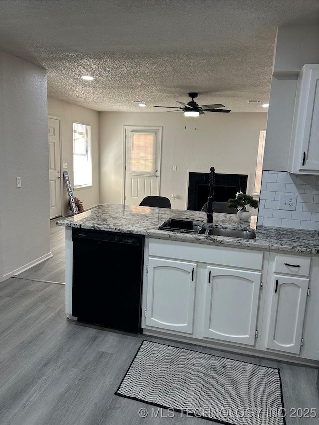 kitchen featuring dishwasher, a peninsula, white cabinets, a ceiling fan, and a sink