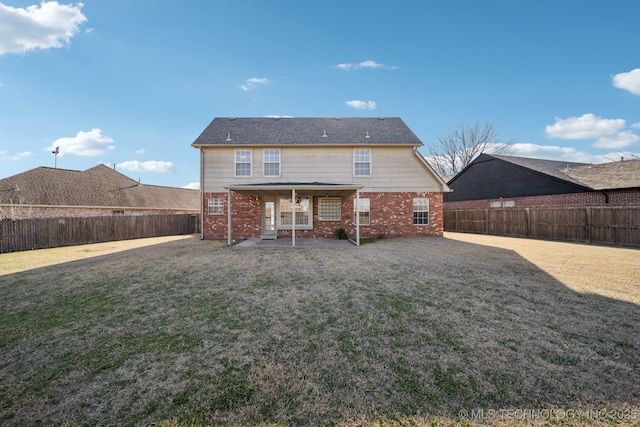 rear view of house with a patio, a lawn, a fenced backyard, and brick siding