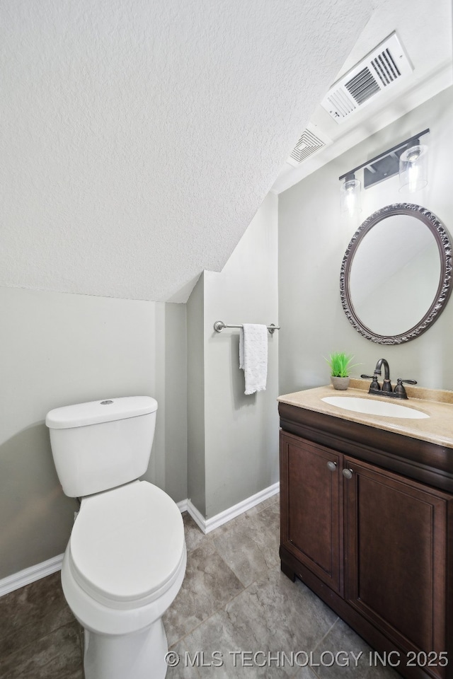 bathroom featuring baseboards, toilet, vanity, lofted ceiling, and a textured ceiling