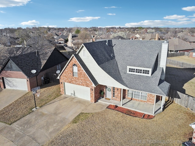 view of front of property featuring brick siding, a front lawn, fence, concrete driveway, and a chimney