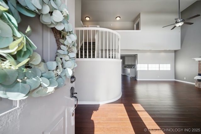 foyer entrance featuring a ceiling fan, a high ceiling, wood finished floors, and baseboards