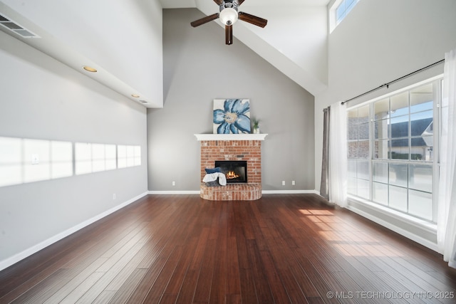 unfurnished living room with a wealth of natural light, wood-type flooring, a brick fireplace, and ceiling fan