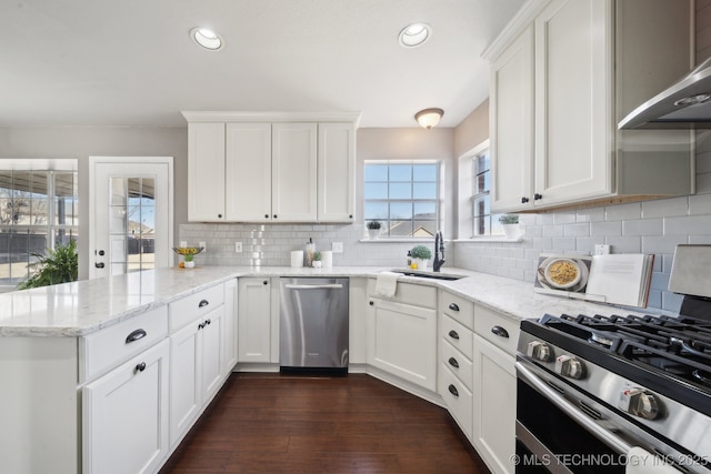 kitchen with white cabinets, appliances with stainless steel finishes, a peninsula, and a sink