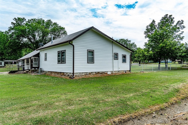 view of side of home with a lawn and fence