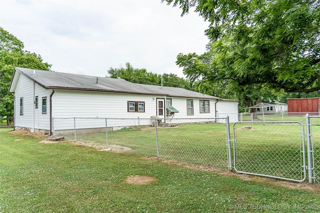 rear view of property featuring a gate, a lawn, and fence