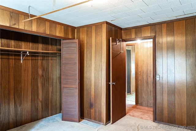 unfurnished bedroom featuring a closet, carpet floors, and wooden walls