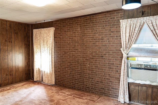 carpeted spare room with wooden walls, cooling unit, and brick wall