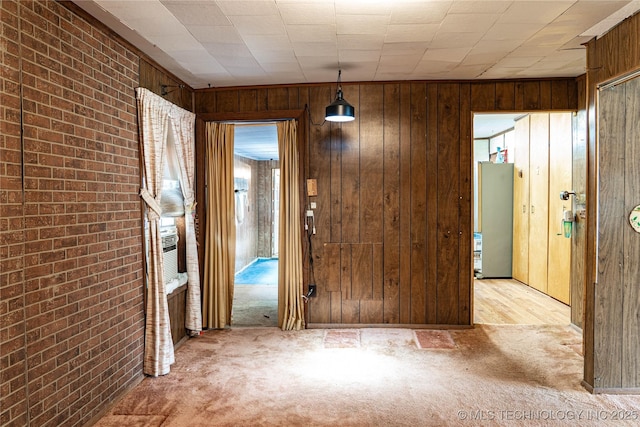 interior space featuring light carpet, brick wall, and wood walls