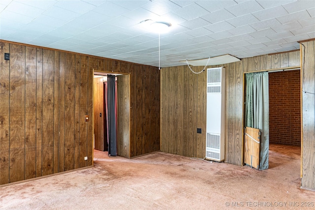 spare room with carpet, a heating unit, and wood walls