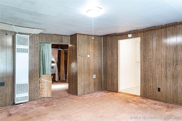 spare room featuring a heating unit, carpet floors, and wood walls