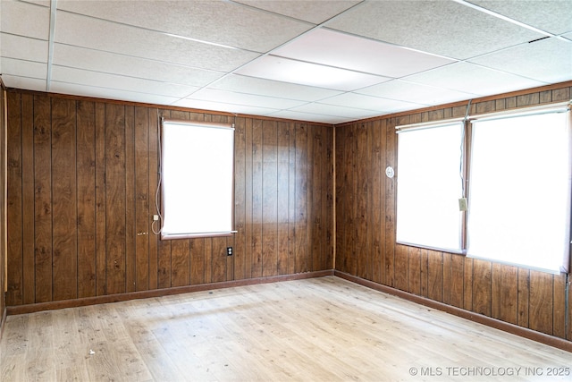 unfurnished room with a paneled ceiling, plenty of natural light, baseboards, and wood finished floors