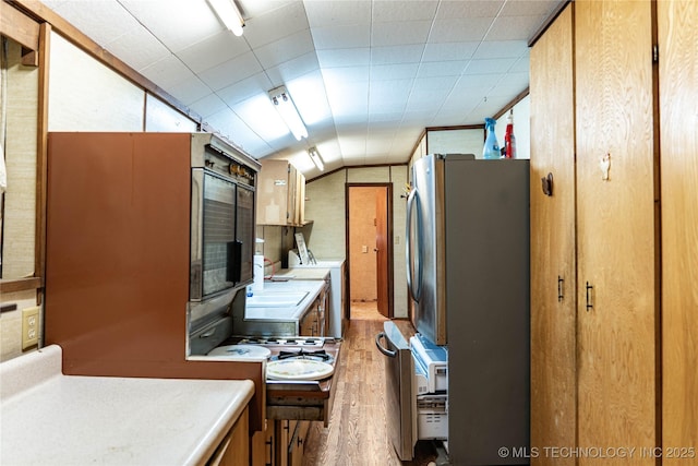 kitchen featuring light wood-style flooring, washer / clothes dryer, freestanding refrigerator, light countertops, and lofted ceiling