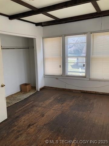 unfurnished bedroom with beamed ceiling, coffered ceiling, a closet, and hardwood / wood-style floors