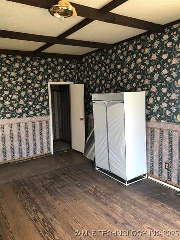 unfurnished room featuring wallpapered walls, beamed ceiling, wood finished floors, and coffered ceiling