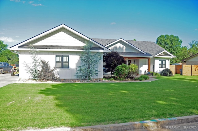 view of front of property featuring a front yard, fence, a standing seam roof, a shingled roof, and board and batten siding