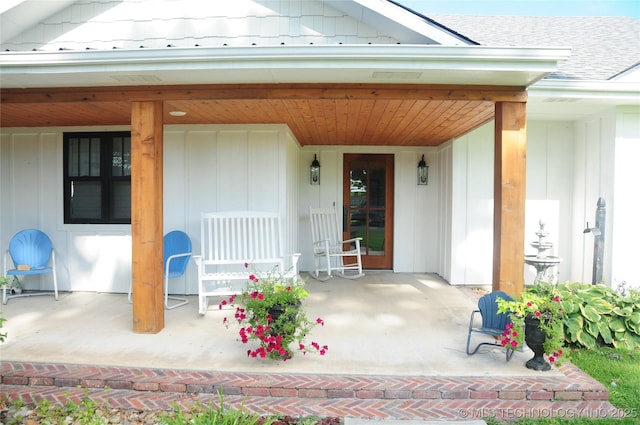 doorway to property featuring a porch and roof with shingles