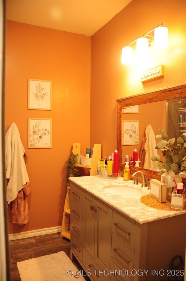 bathroom with baseboards, wood finished floors, and vanity