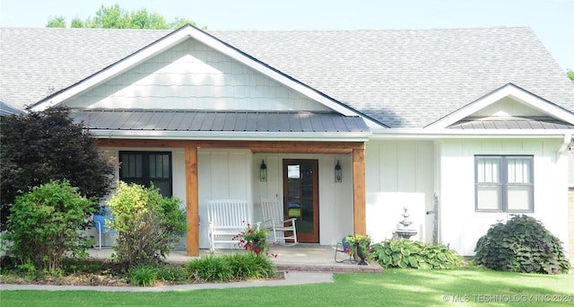 view of front facade with a porch, a shingled roof, a front lawn, and board and batten siding